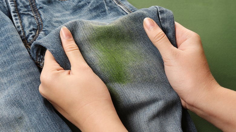 hands holding grass stained jeans