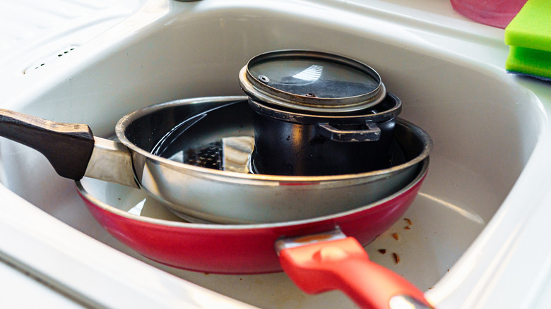 dirty pots and pans piled in kitchen sink