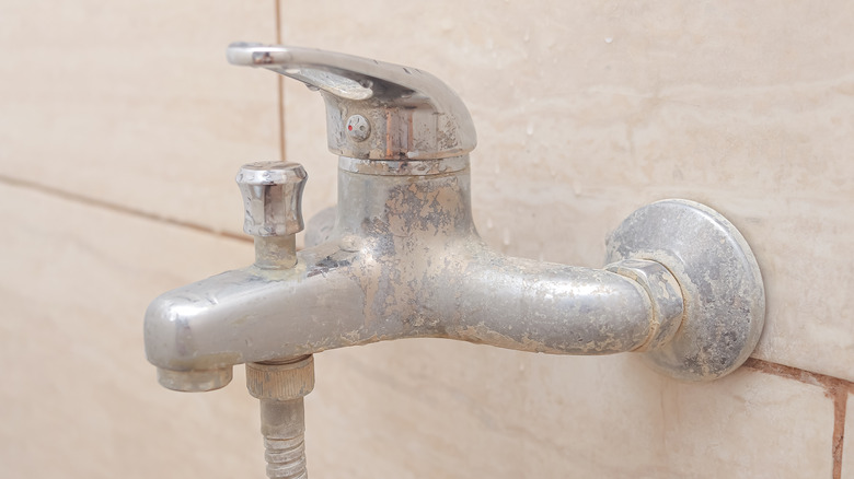 Limescale buildup on a faucet with tile in the background