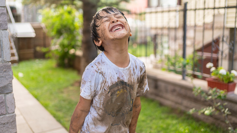 smiling boy covered in mud