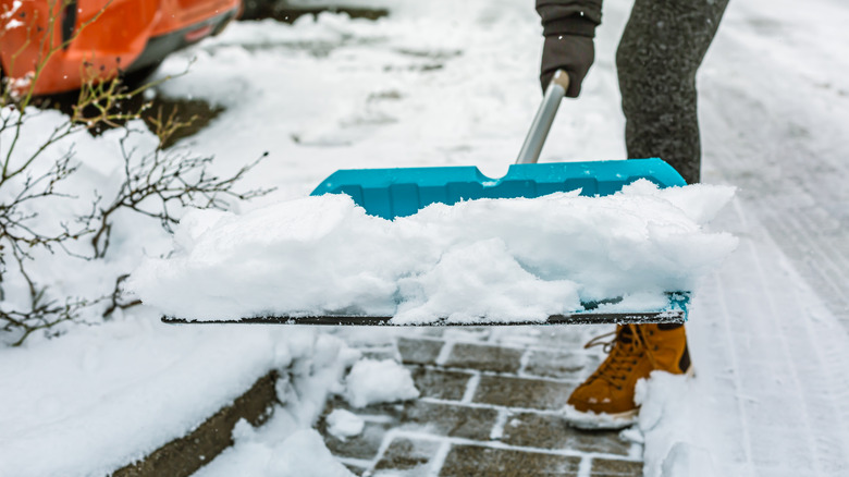Shoveling snow on a pathway away from the driveway