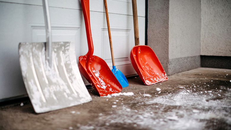 Row of various snow shovels in a garage