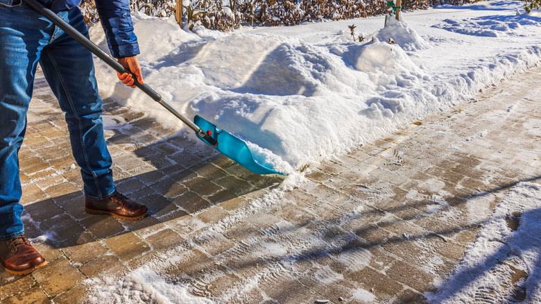 Person shoveling a brick walkway