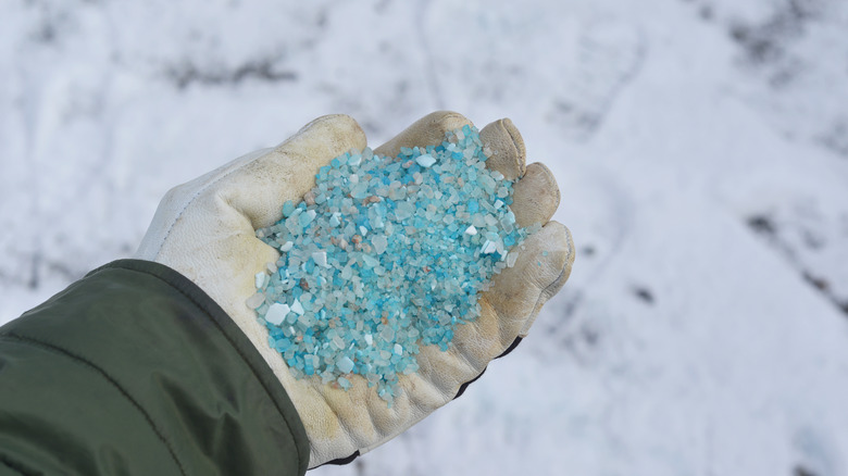 Person spreading ice melt crystals with a gloved hand