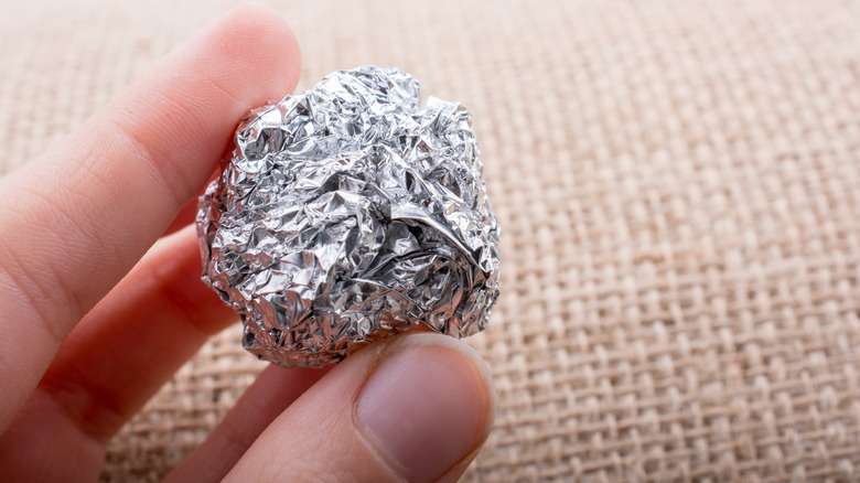Person holding aluminum foil ball