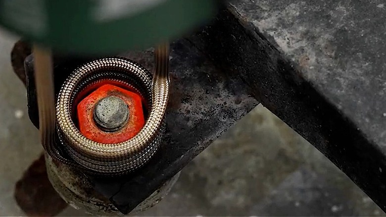 The coil from an induction heater is placed on a rusted bolt to make removal easy