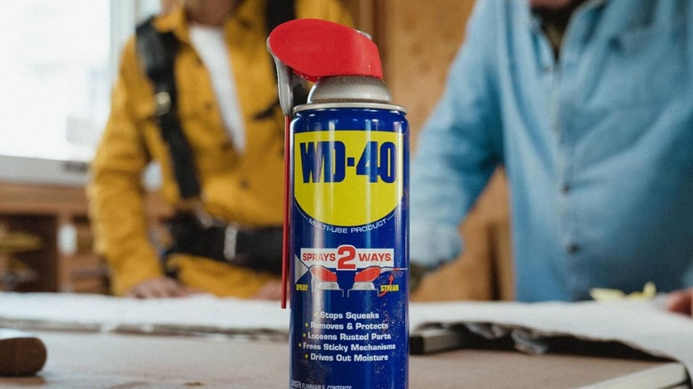 bottle of wd-40 on table near workers