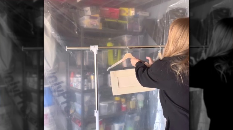 Woman hanging cabinet door on clothing rack