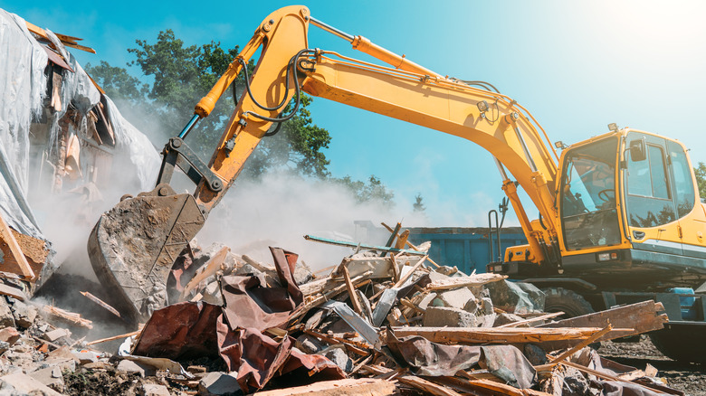 Backhoe demolishing house