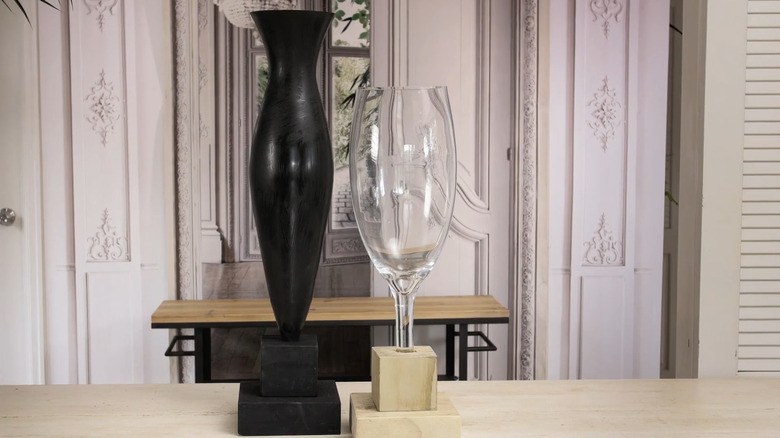 Black vase with a black wood base and clear vase with a plain wood base