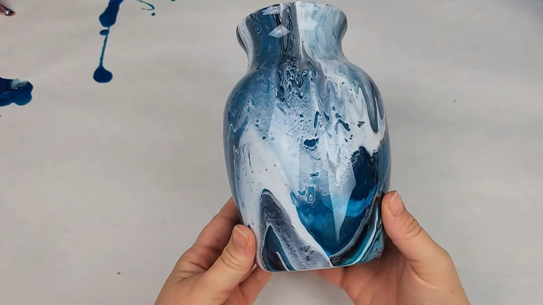 Person holding a small vase that's covered in a blue and white poured design