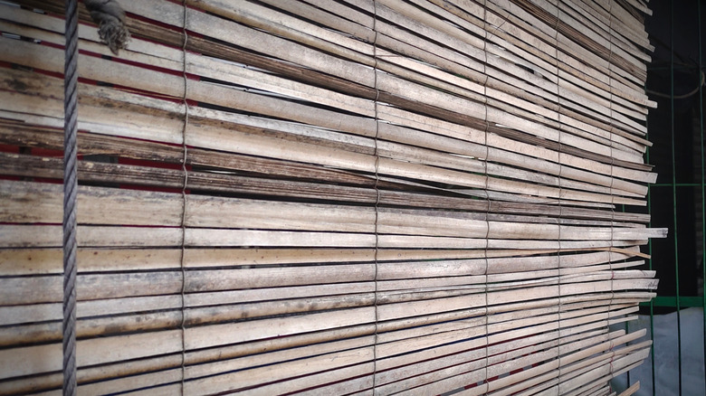 Bent and broken old wooden window blinds on a window.