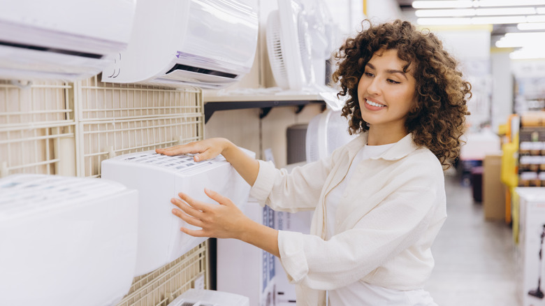 A smiling person is looking at different AC models in a store