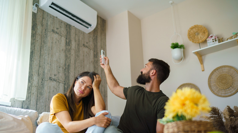 An annoyed couple is trying to turn on their living room AC
