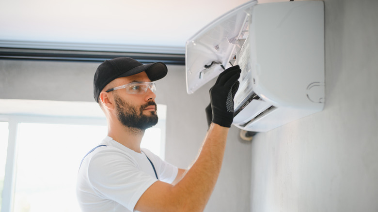 A serious-looking technician repairing an AC