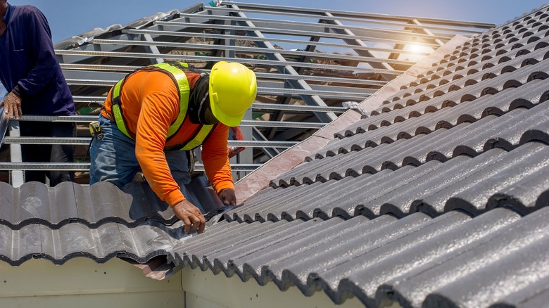 worker fixing roof tiles