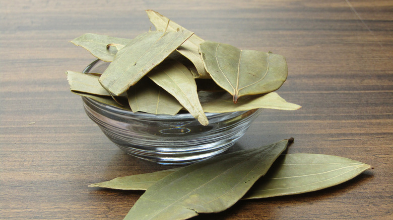 Dry bay leaves in a small glass bowl on a table