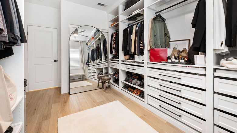 A walk-in closet with a wooden floor.