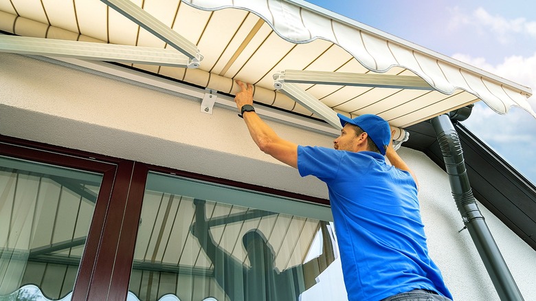 A person installs a fabric awning