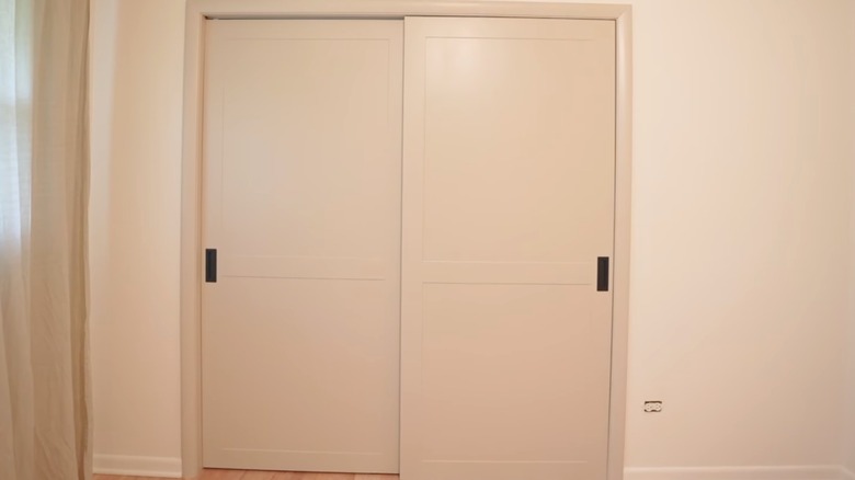 White shaker style doors with black hardware on a closet.