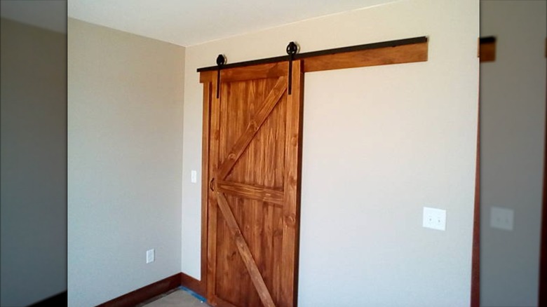 A brown wood sliding barn door with black track.