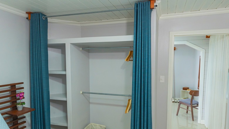 An opened blue curtain in front of an empty closet.