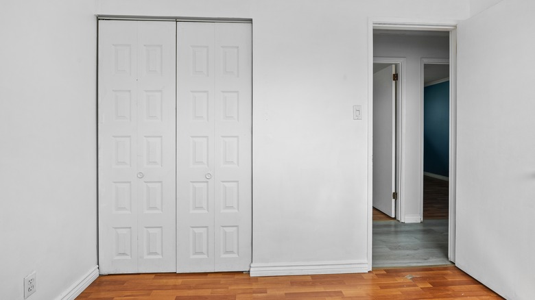 Two white closet doors in a white room.