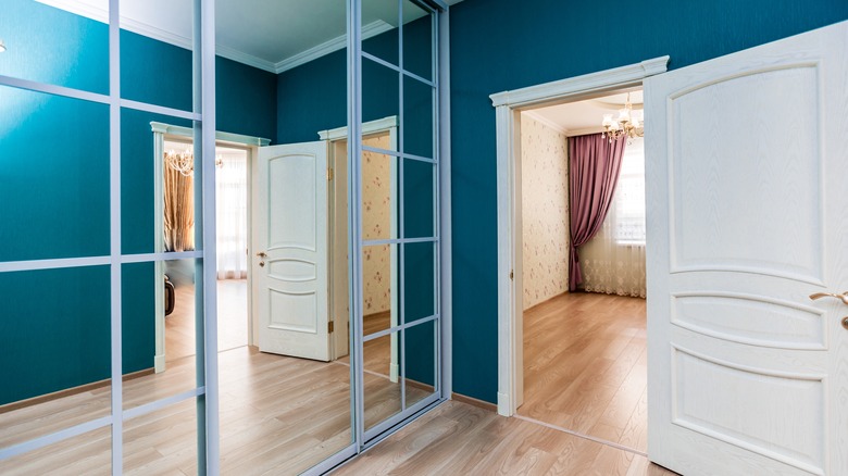 A closet with a mirrored door next to an open door.