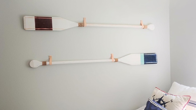 A pair of oars mounted on the wall using leather straps.