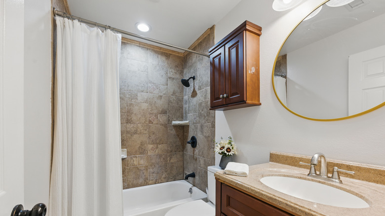 Small bathroom with a brown-tiled shower enclosure and a white shower curtain.