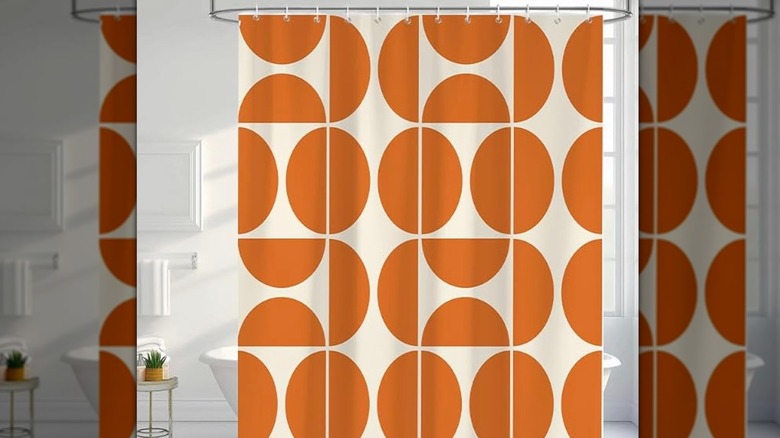 A white bathroom with an orange-patterned shower curtain that has a semicircle print.