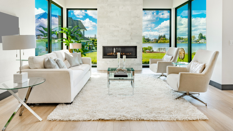 Modern living room with neutral furniture and a stark white, shag rug.