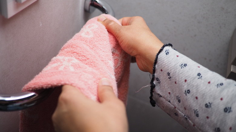 woman placing a towel on towel rack