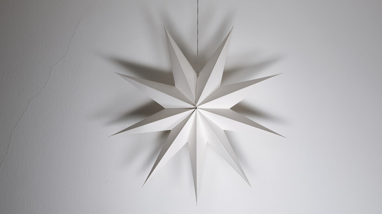 A white paper star hanging in front of a white wall