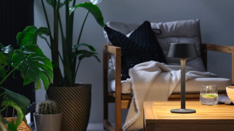A balcony or patio with plants and a black IKEA portable lamp on a table