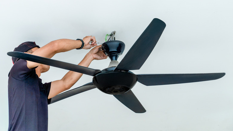 a man taking an old ceiling fan down to replace it