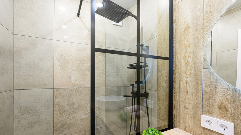 A black-framed glass shower screen has 3 glass panels