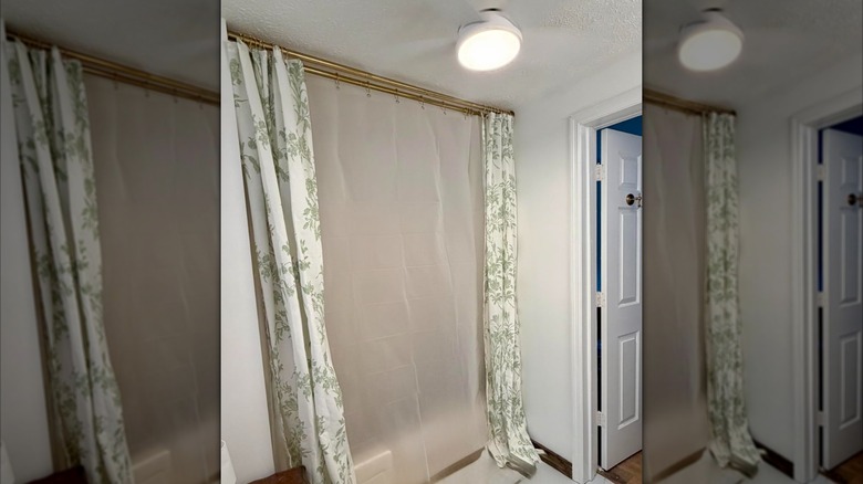 A double shower curtain rod in gold with two curtains hung on each rod
