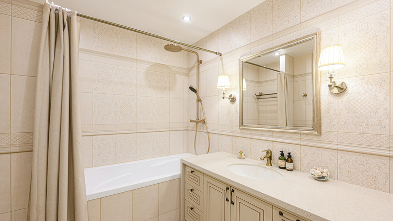 A beautiful bathroom interior containing a bath with a beige shower curtain.
