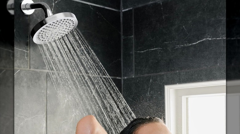 SparkPod shower head being used in a shower, with water flowing down onto someone's head