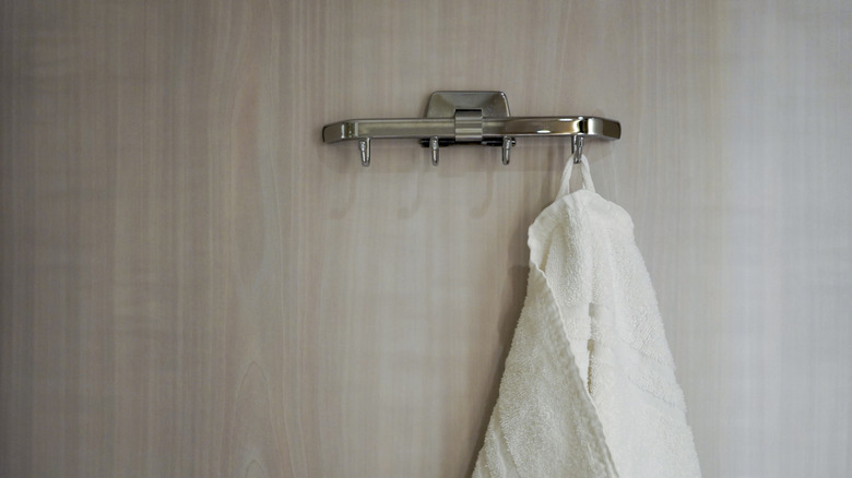Towel hook rack on wall with white towel hanging.