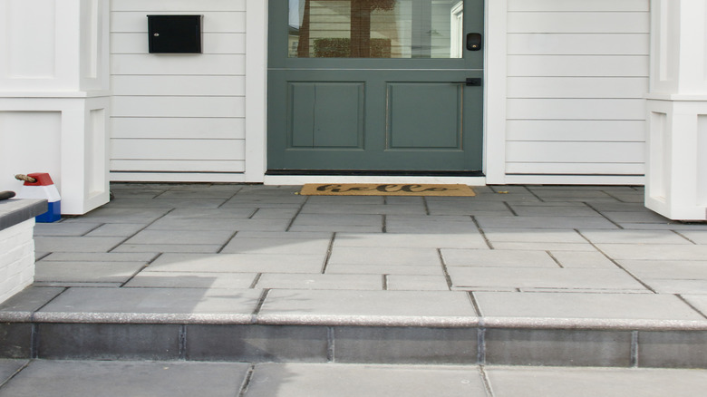 Close-up view of a half lite front door next to a mailbox and wall lights