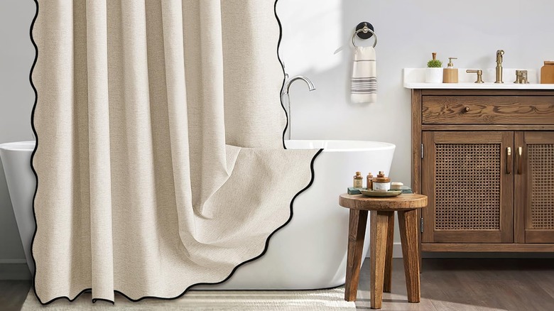 A product shot of the MIULEE beige scalloped shower curtain hanging over a white bathtub.