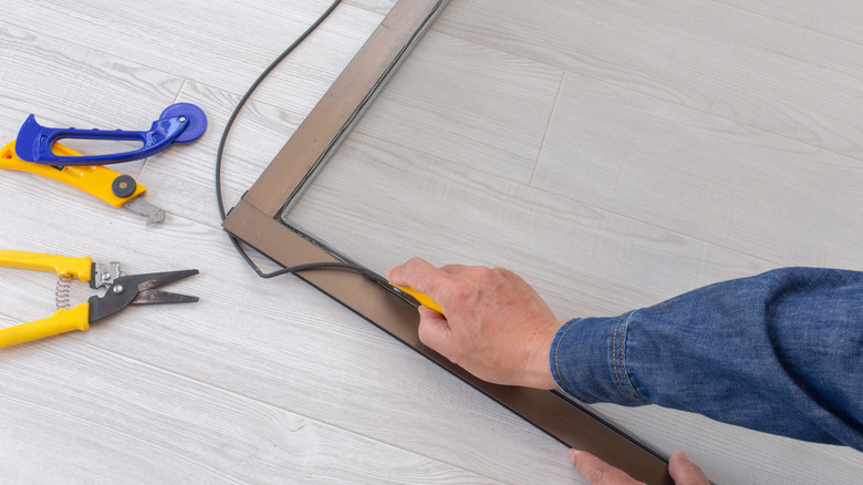 Person replacing spline on window screen