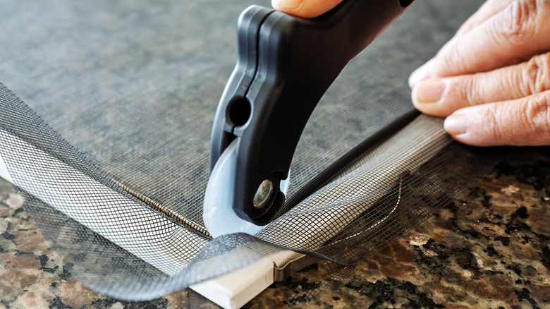 Person using a window screen rolling tool