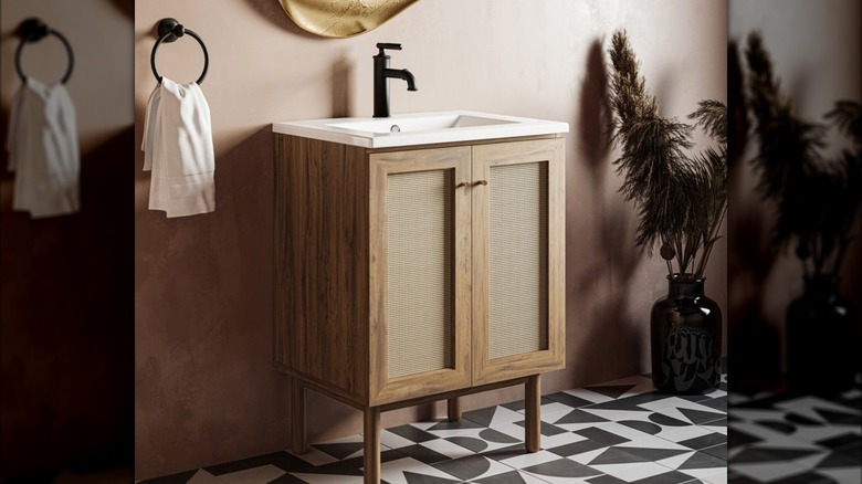 an oak and rattan mid-century modern vanity on a black and white tiled floor
