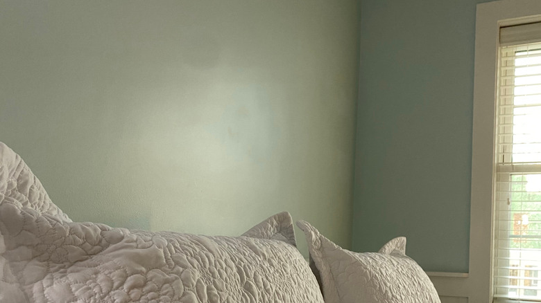 White pillow shams on a bed, with mint green walls in background.