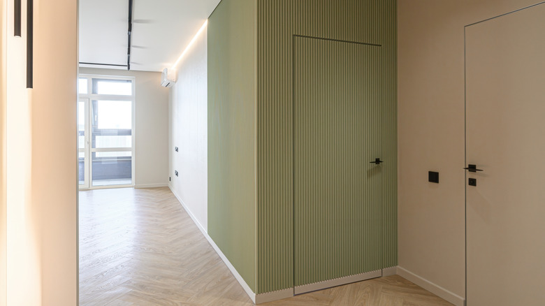 Hallway with fluted accent wall painted in a medium olive green