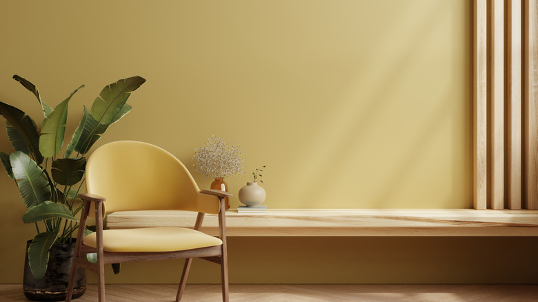 Buttery yellow wall with yellow accent chair and potted plant