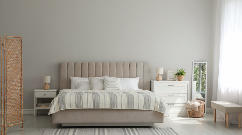 Bed with tufted greige headboard in front of medium-warm gray wall.